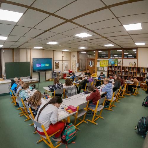Blick in eine Schulklasse, die Schülerinnen und Schüler sitzen an den Tischen und lernen